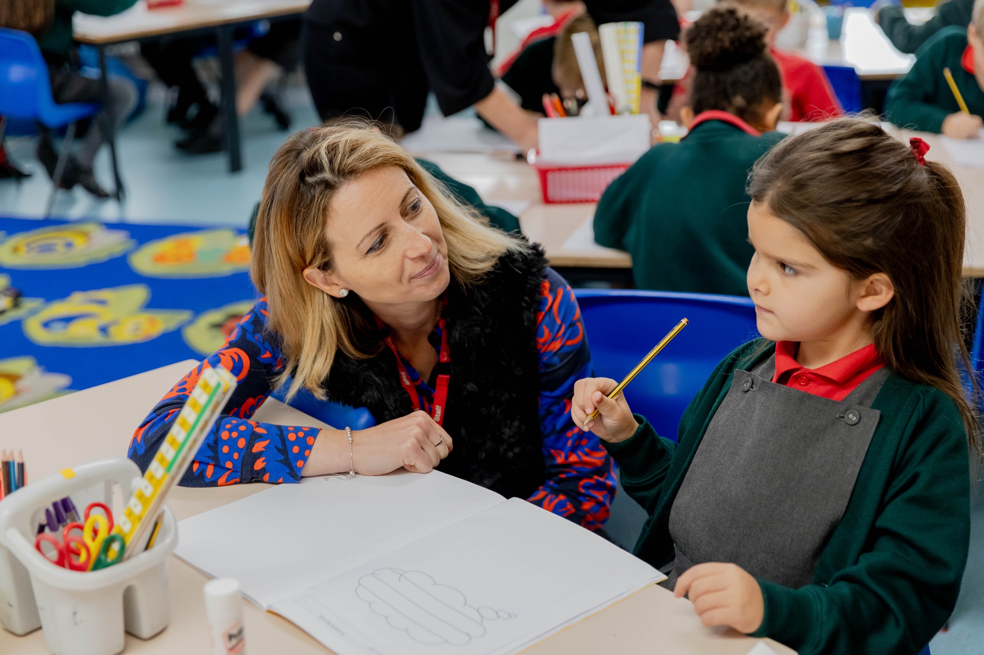 One of our TAs helping a child learn in a Greensand school
