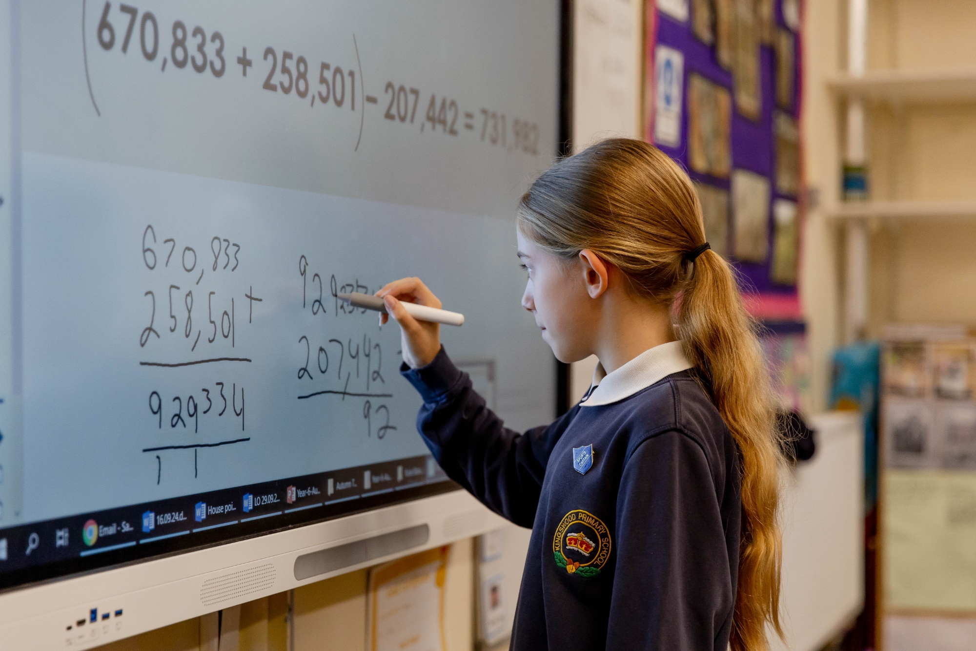 Kingswood child writing on the smart board in a maths class